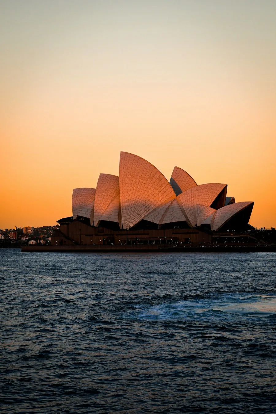 Sydney Opera House beside the harbour at sunset