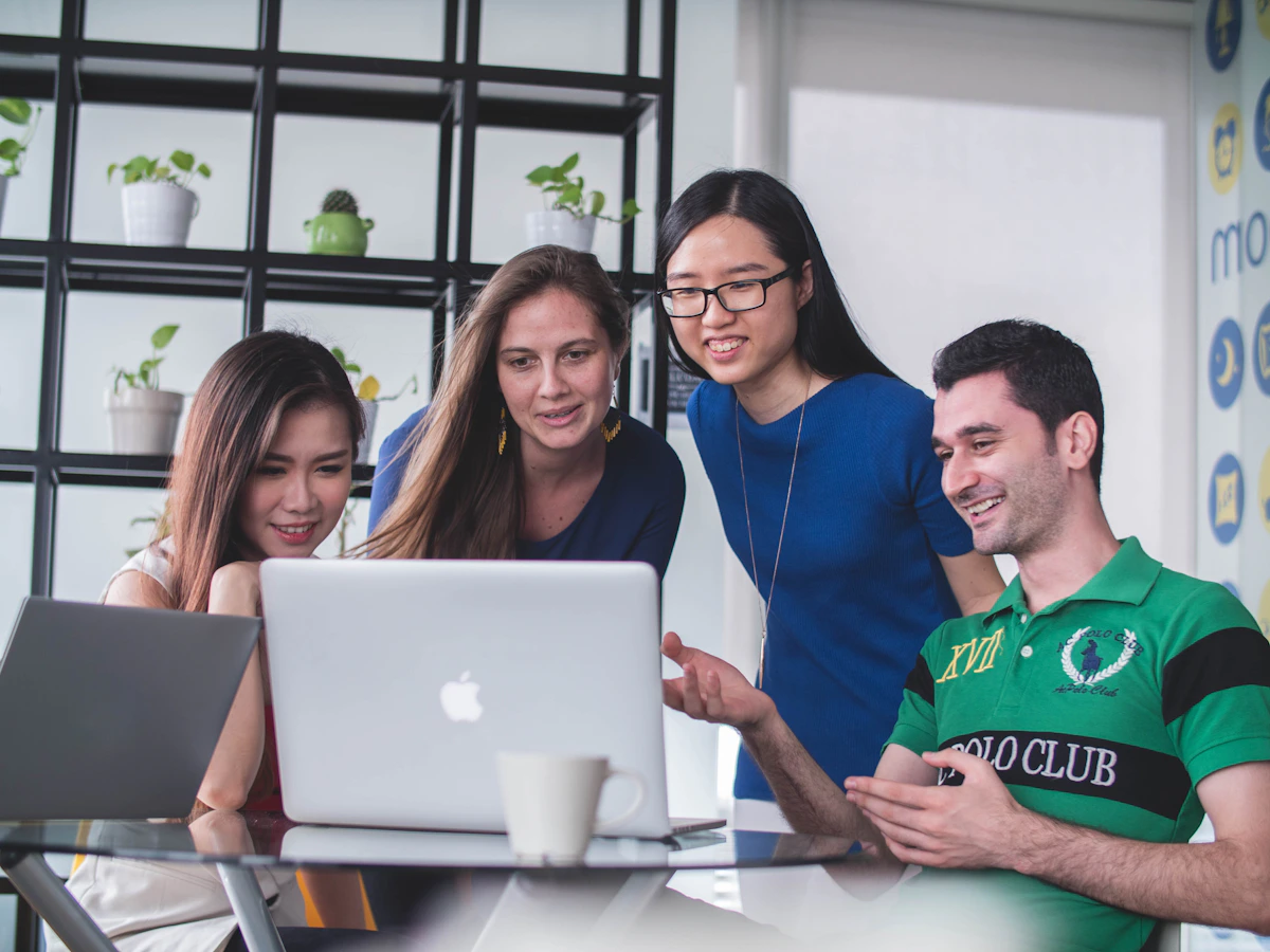 Colleagues collaborating around a laptop in a modern workplace